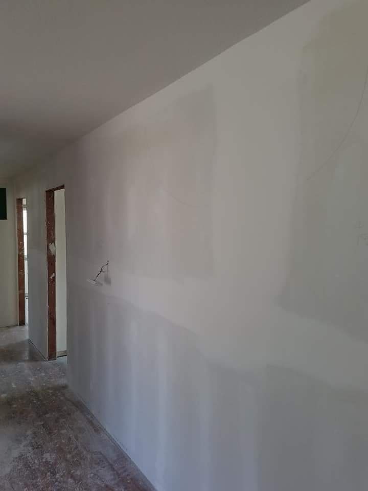 A hallway with a white wall and two doors.