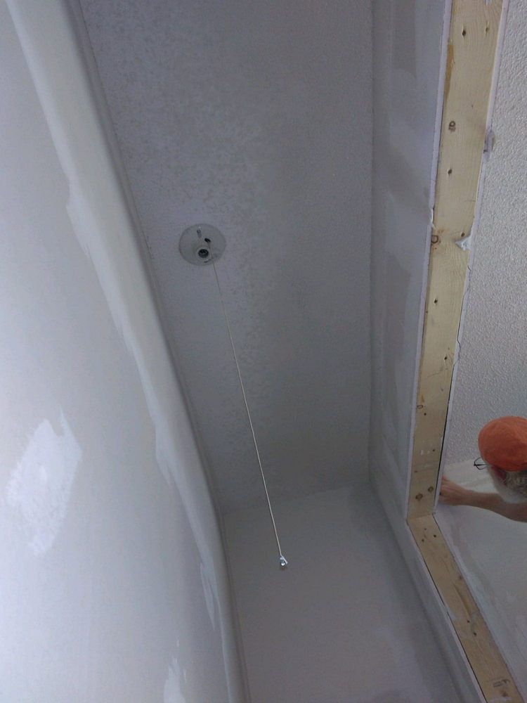 A person is cleaning a shower stall with a sponge.