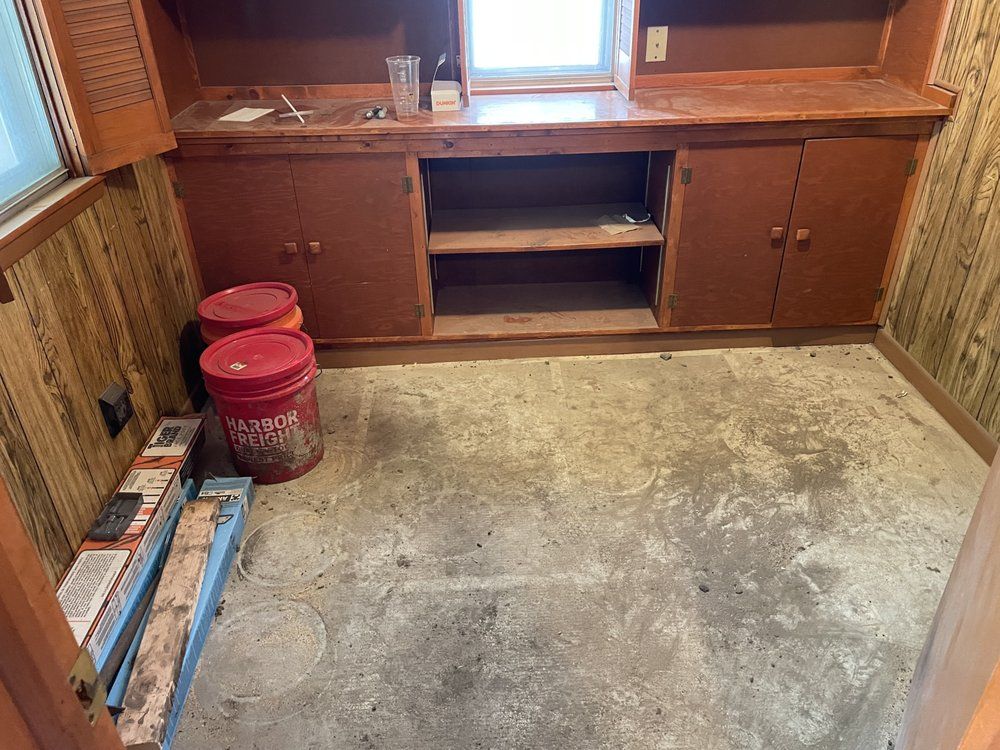 A room with a lot of cabinets and buckets on the floor.