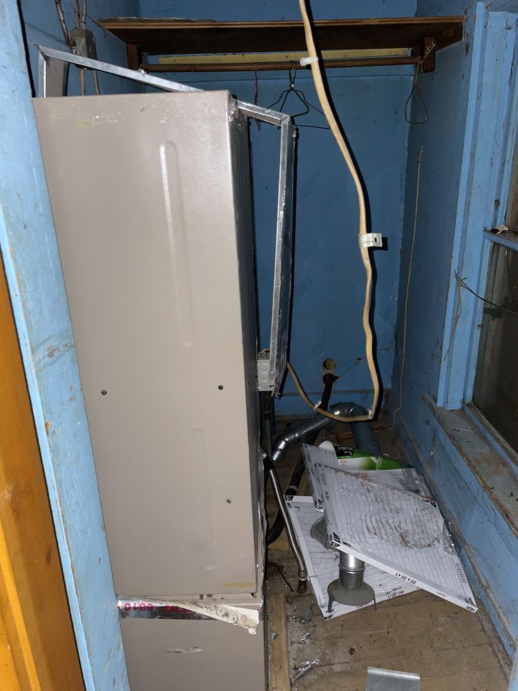 A refrigerator is sitting in a corner of a room next to a window.