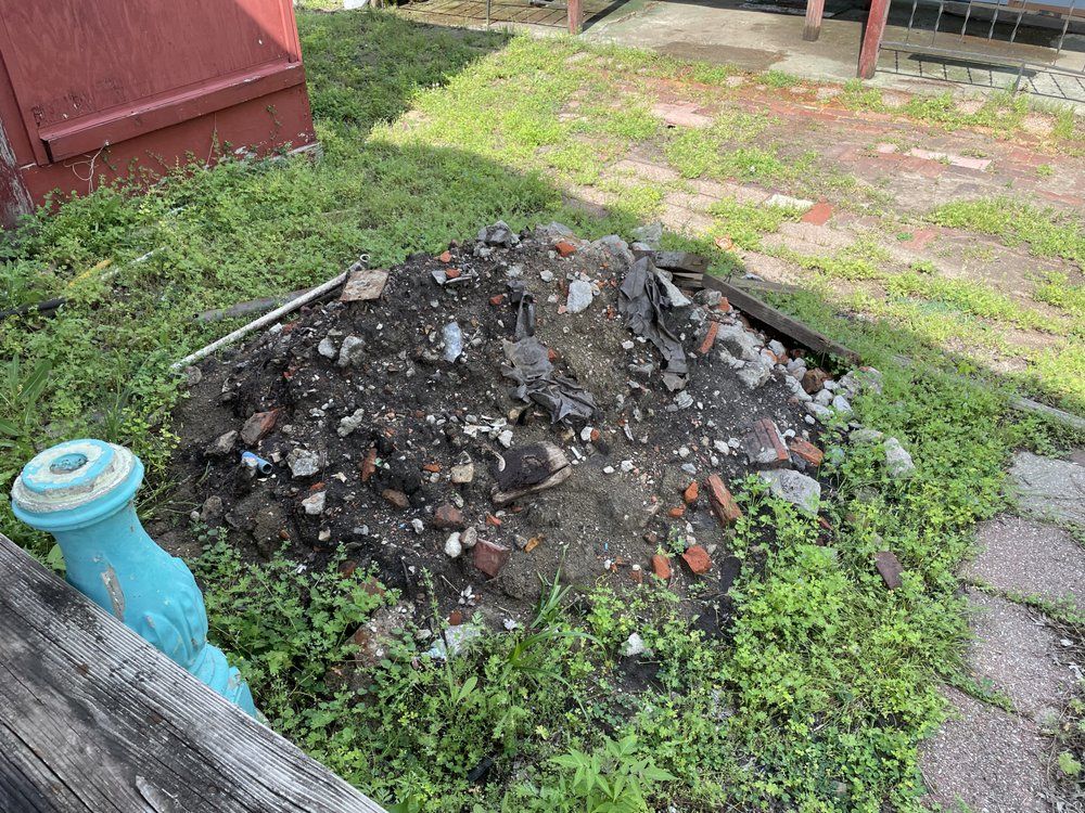 A pile of rocks is sitting in the middle of a yard next to a wooden fence.
