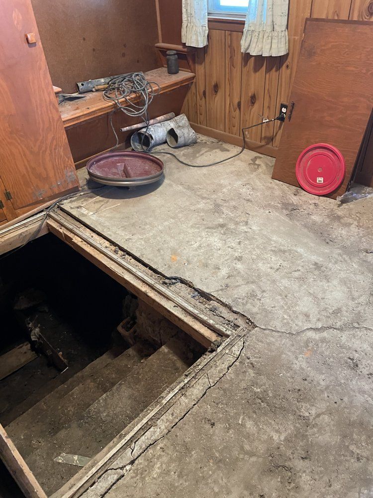 A room with a hole in the floor and a red plate on the floor.