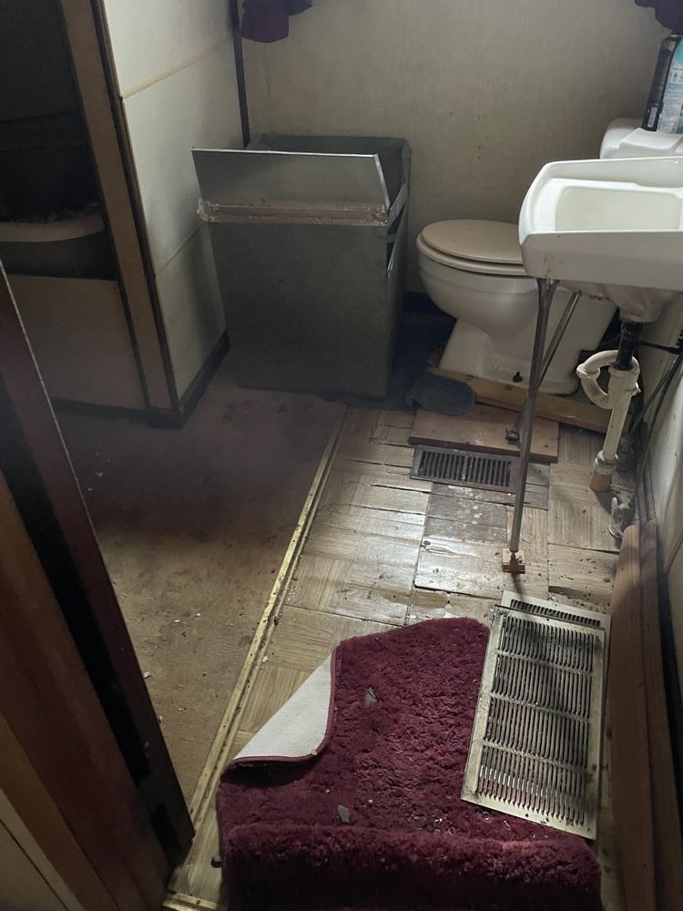 A bathroom with a toilet , sink , and trash can.