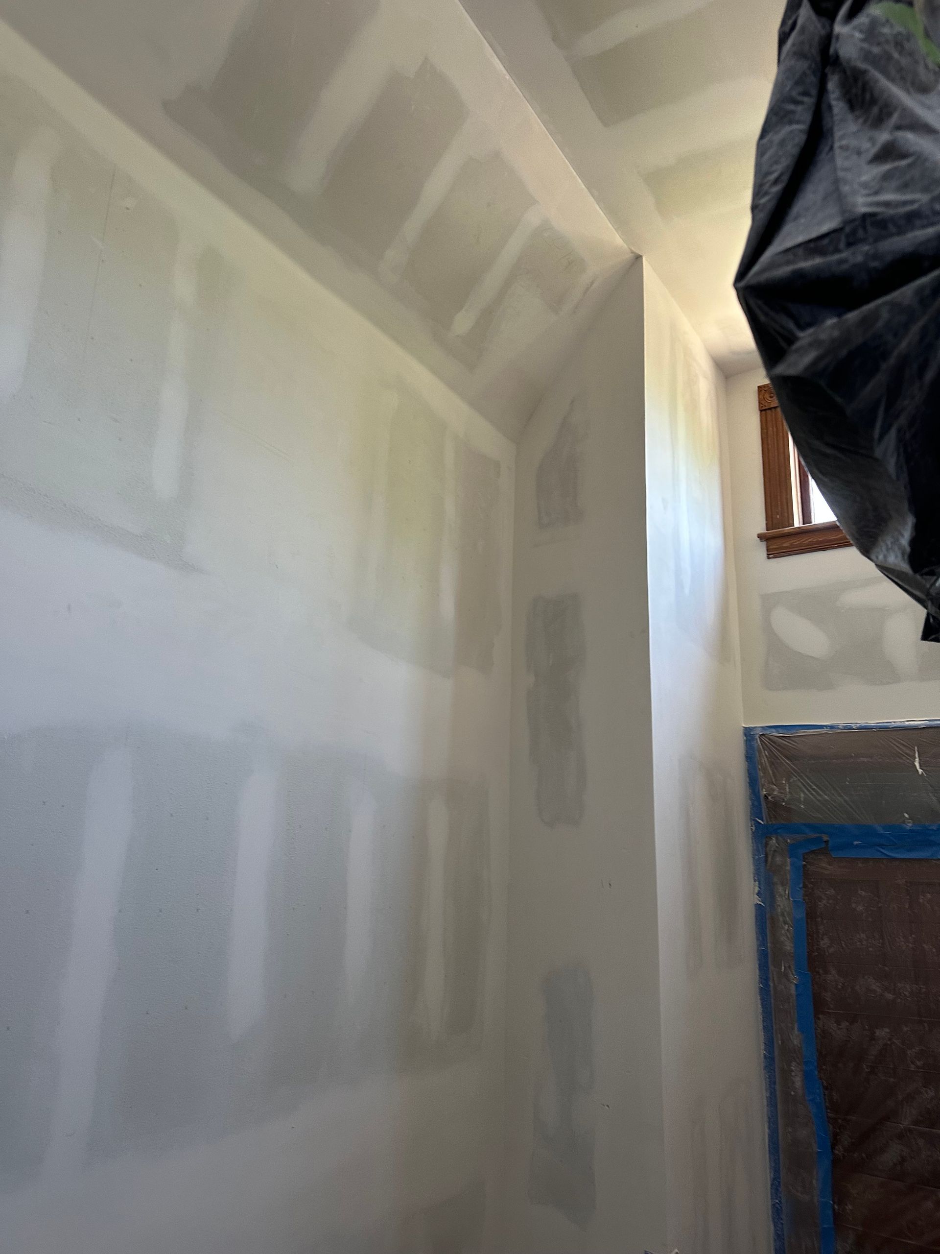 A room with white walls and a black tarp hanging from the ceiling.