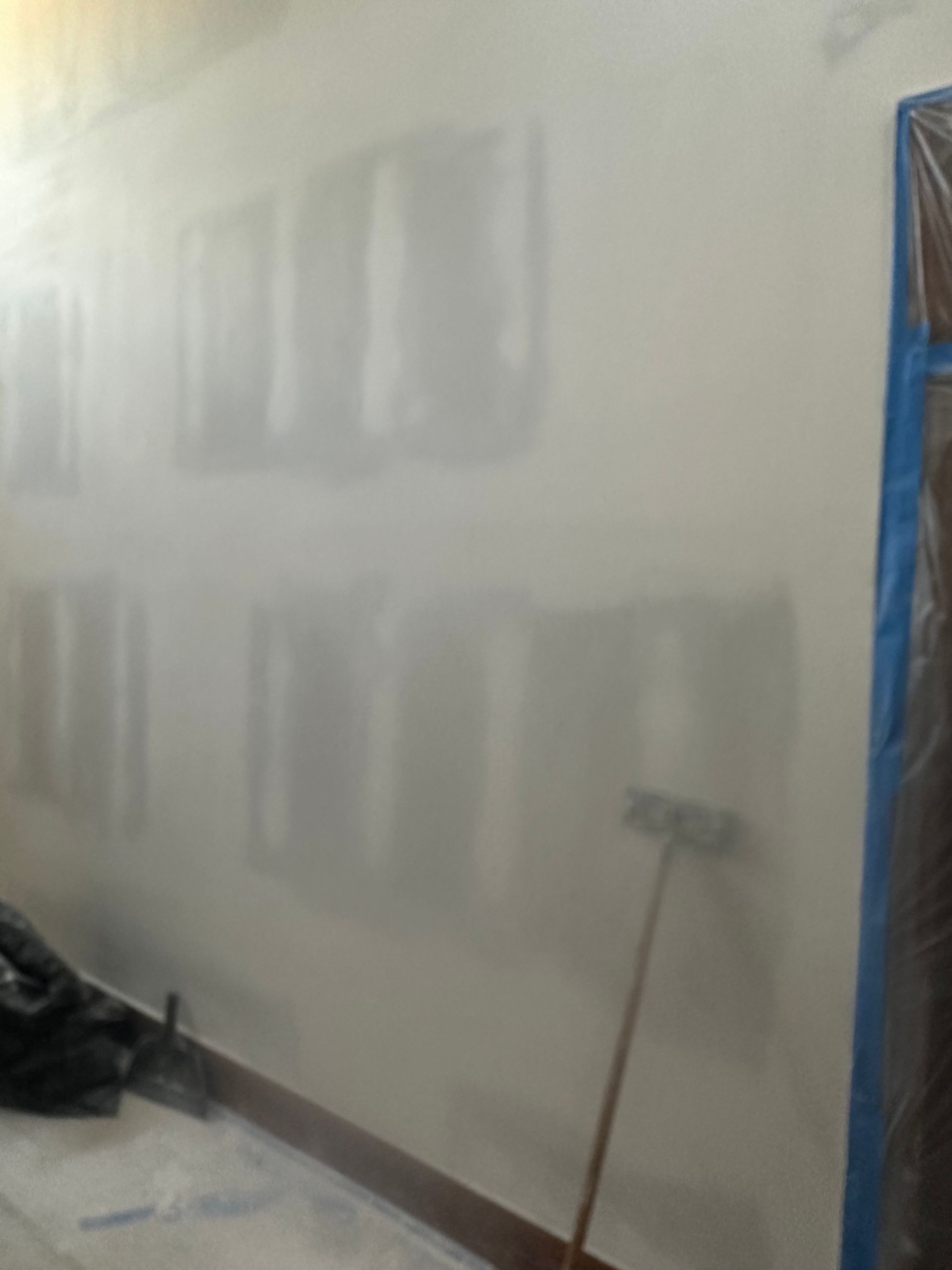 A room with a white wall and a broom.