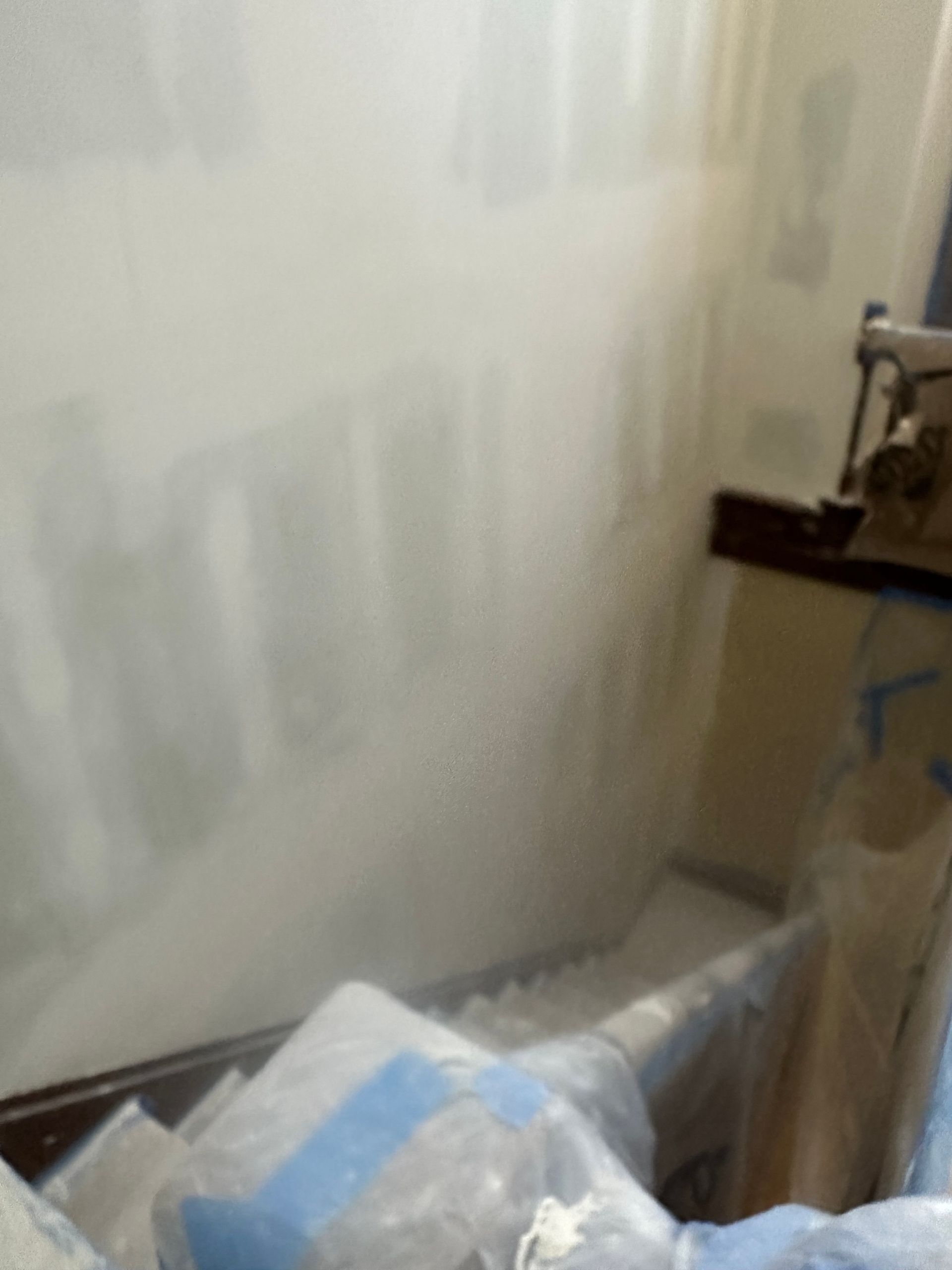 A room with a white wall and a lot of plastic bags on the floor.