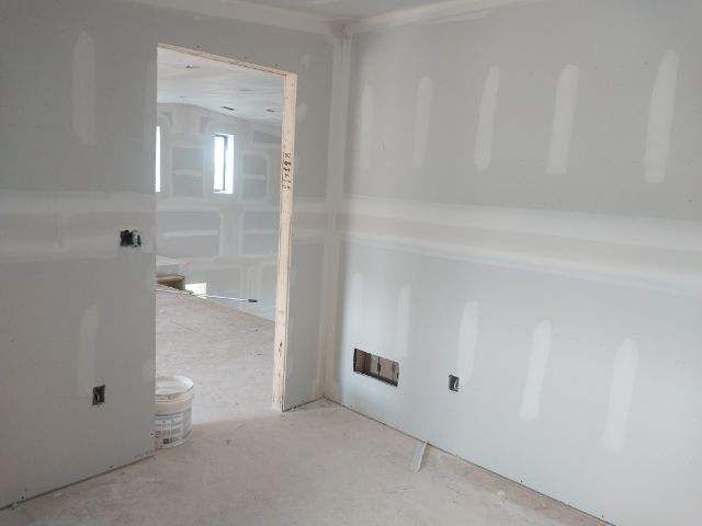 A room with drywall on the walls and a doorway leading to another room.
