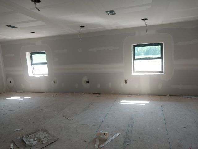 A room with a lot of windows and drywall on the walls.
