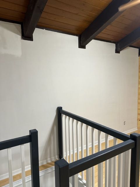 A staircase with white walls and a black railing