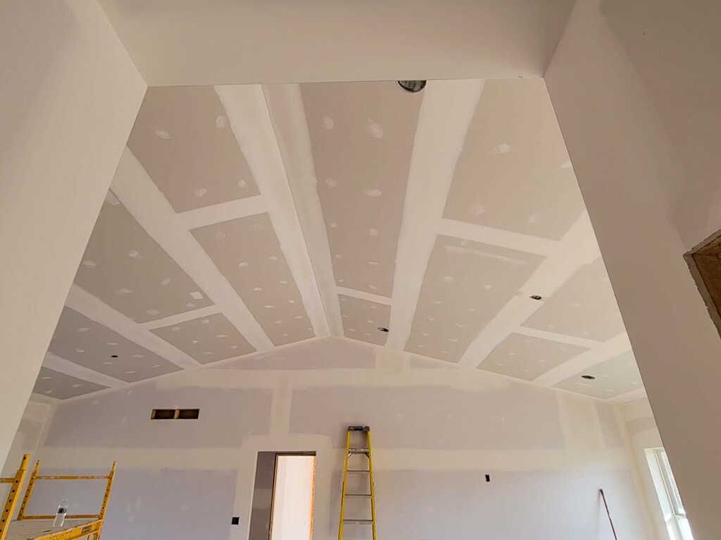 A room with a ceiling that is being remodeled and a ladder.