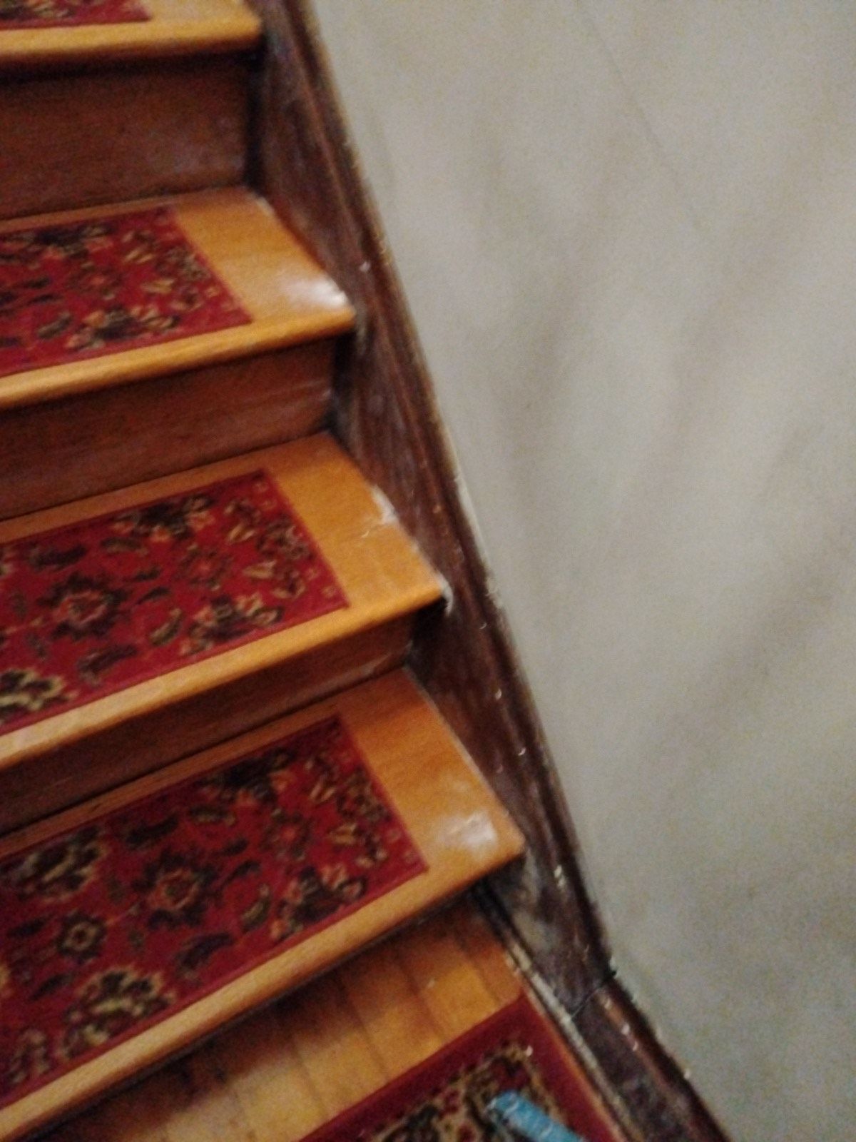 A wooden staircase with a red rug on the steps