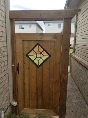 A wooden gate with a stained glass window in the middle of it.