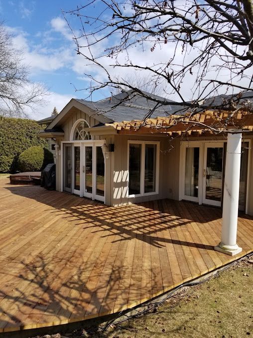 A house with a wooden deck and a pergola in front of it.
