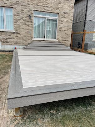 A wooden deck is sitting in front of a brick house.