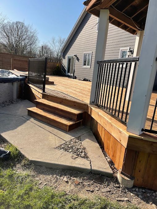 A wooden deck with stairs and a hot tub in the backyard of a house.