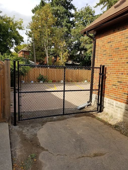 A chain link fence is sitting in front of a brick house.