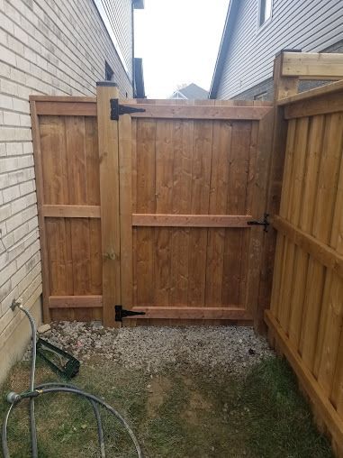 A wooden fence with a gate in the backyard of a house.