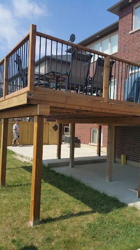 A wooden deck with chairs and a fence in the backyard of a house.