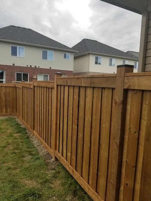 A wooden fence is in the backyard of a house.