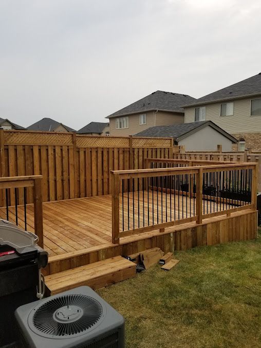 A wooden deck in a backyard with a fence and an air conditioner.