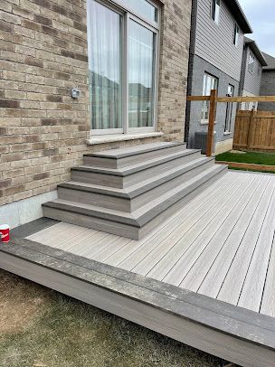 A wooden deck with stairs leading up to a brick house.