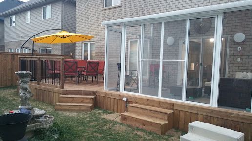 A screened in porch with a yellow umbrella in the backyard of a house.