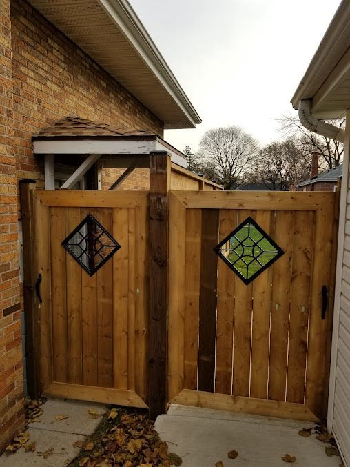 A wooden gate with a stained glass window is between two houses.