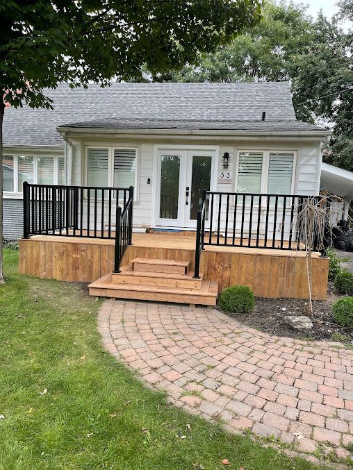 A white house with a wooden deck and stairs in front of it.
