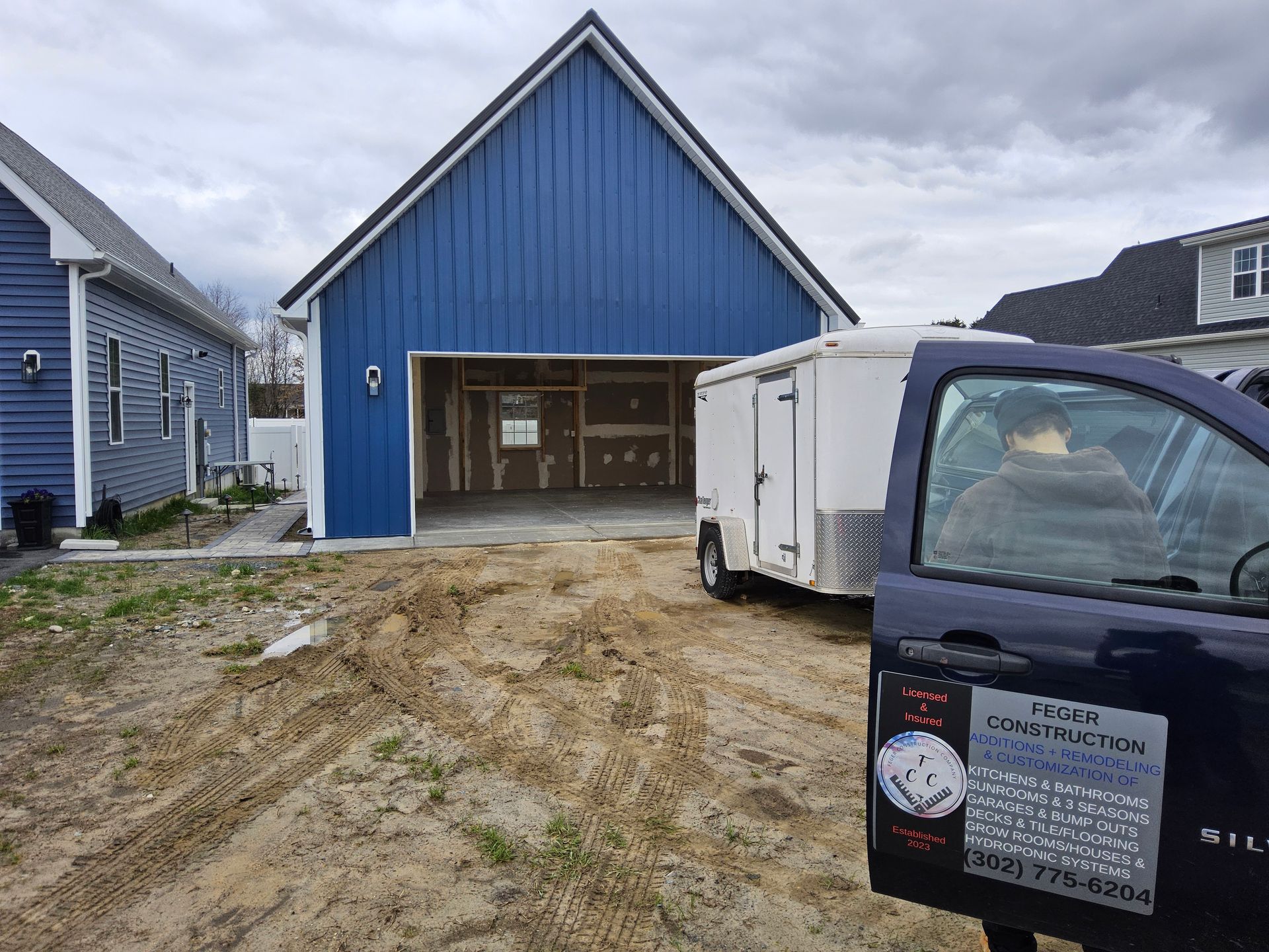 A truck is parked in front of a blue garage under construction.