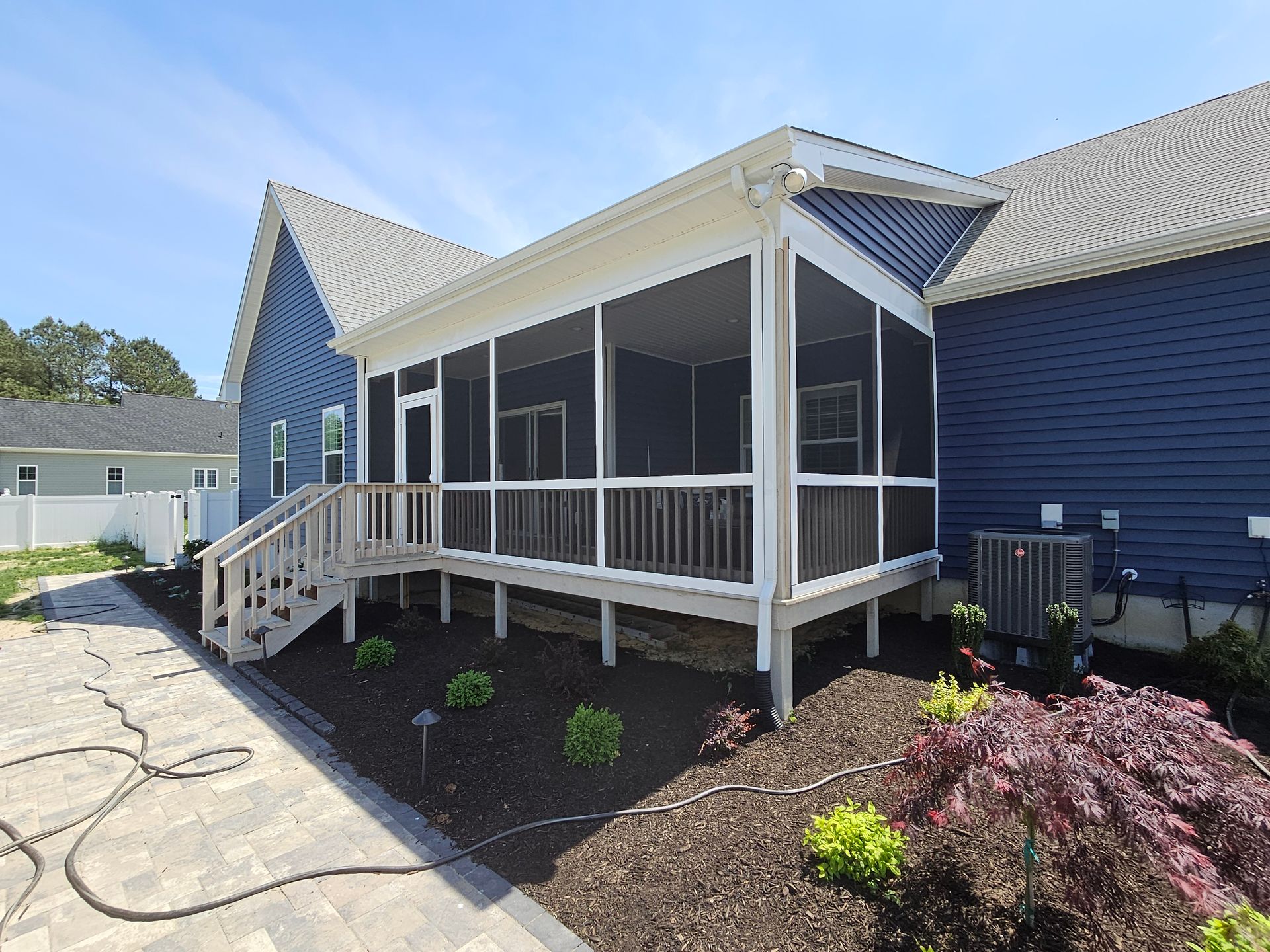 A screened in porch with a blue house in the background