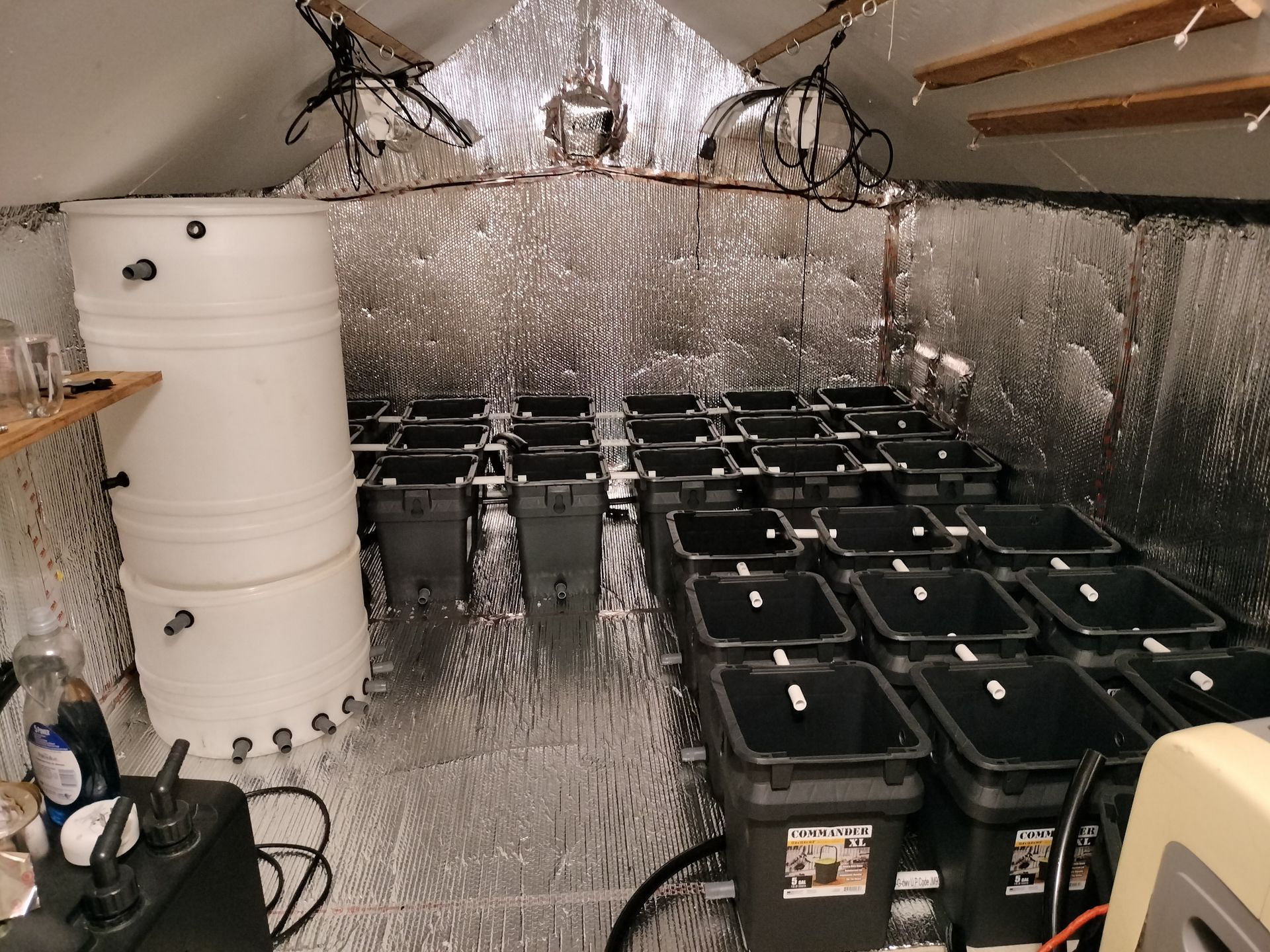 A room with a lot of black bins and a white barrel