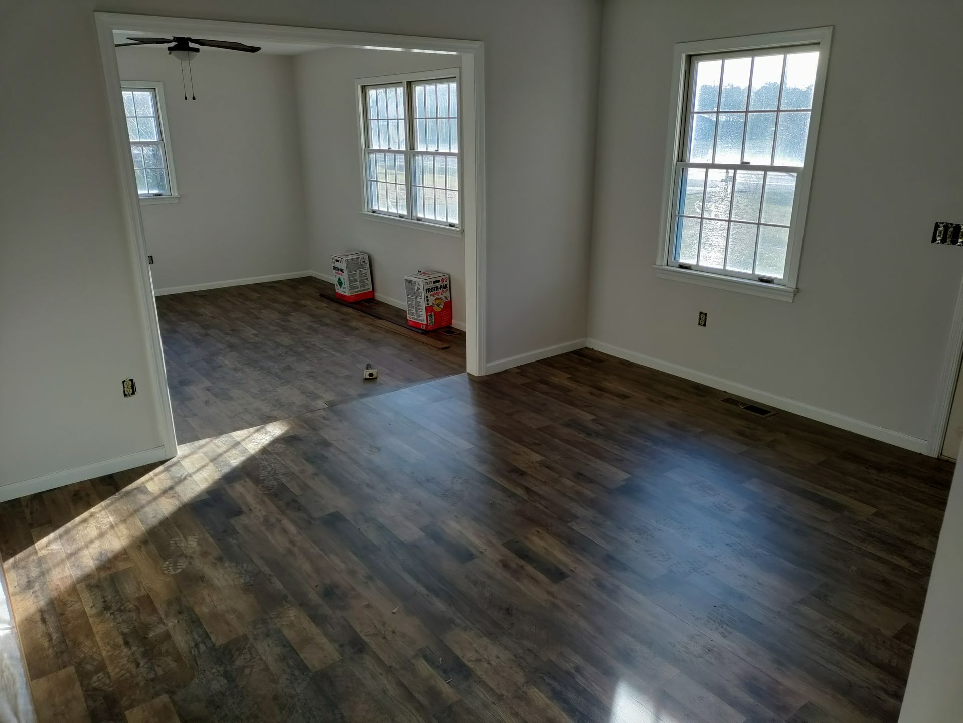 A living room with hardwood floors and two windows.