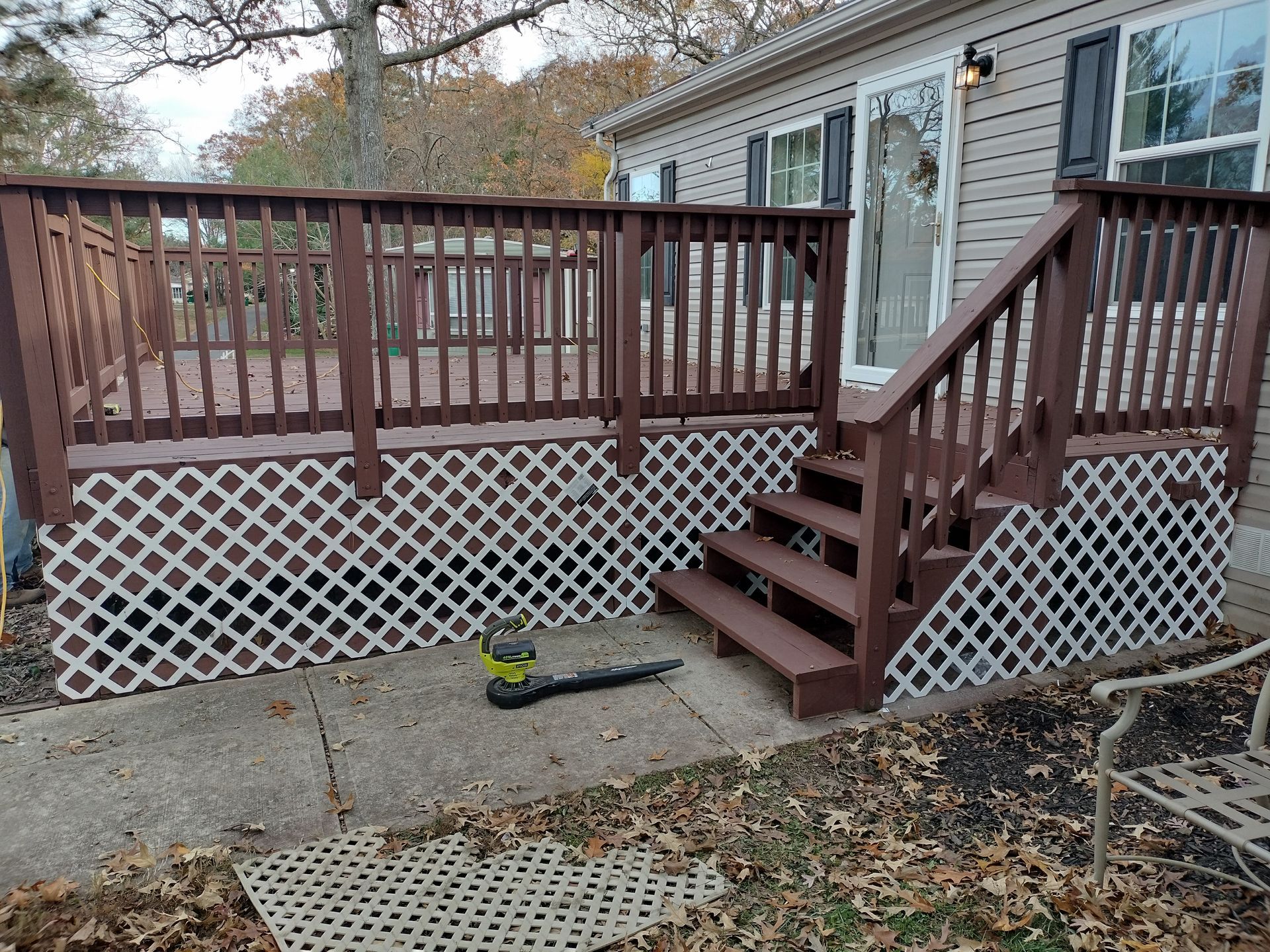 A wooden deck with stairs and a fence in front of a house.