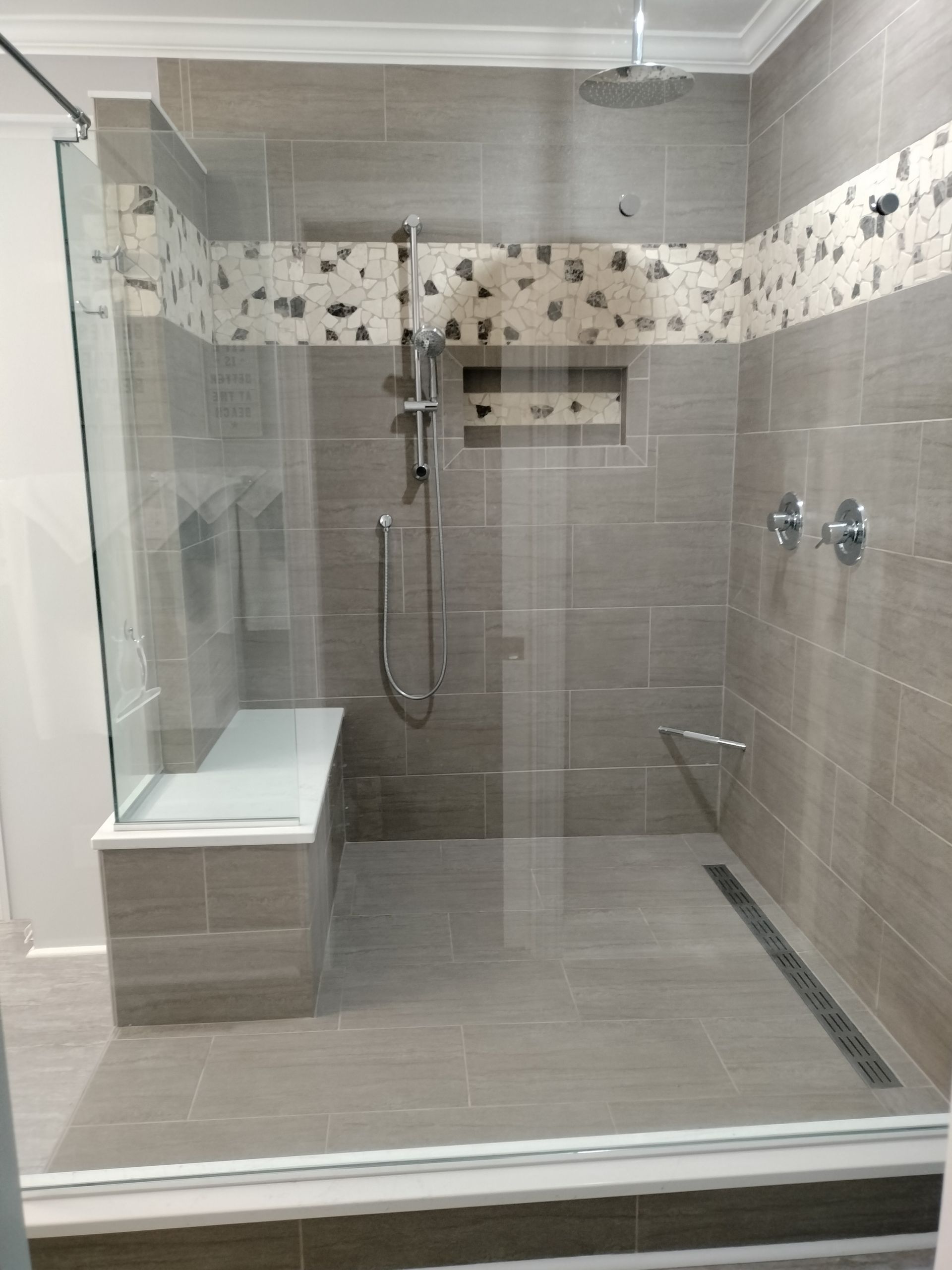 A bathroom with a walk in shower and a bench.