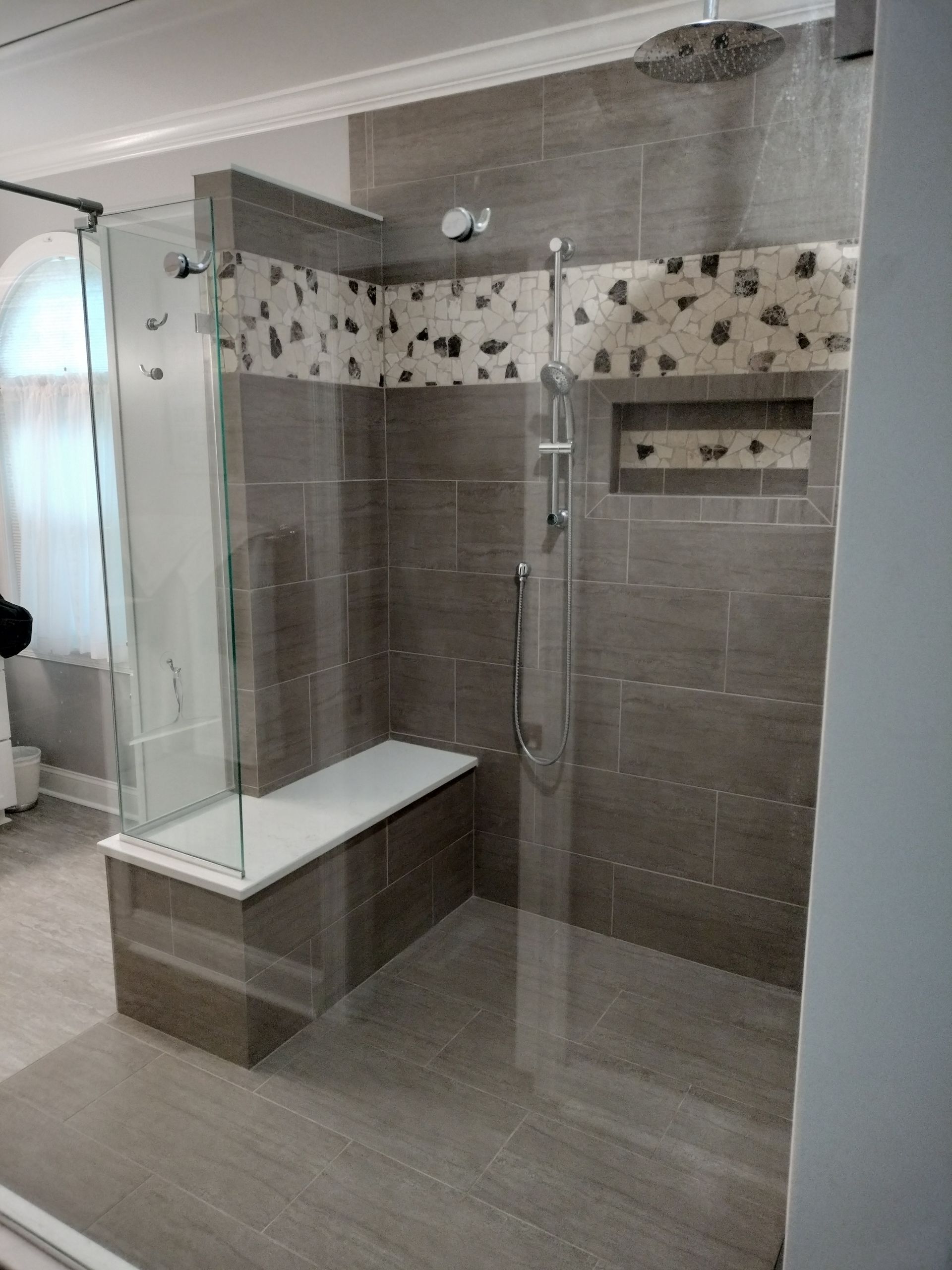 A bathroom with a walk in shower and a bench.