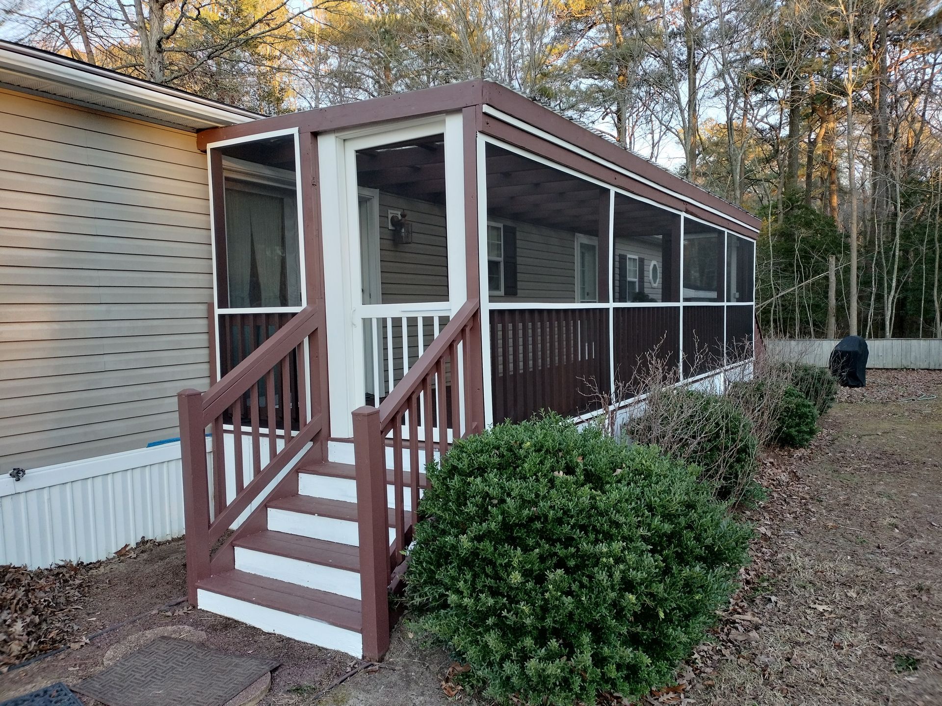 A mobile home with a screened in porch and stairs.