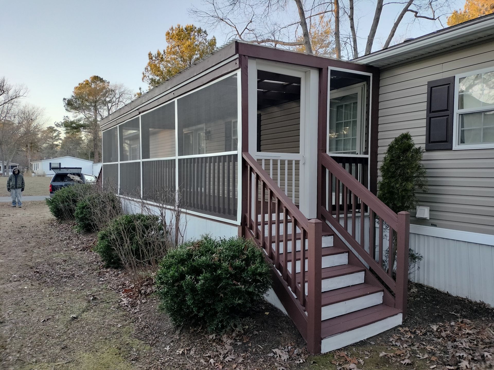 A mobile home with a screened in porch and stairs.