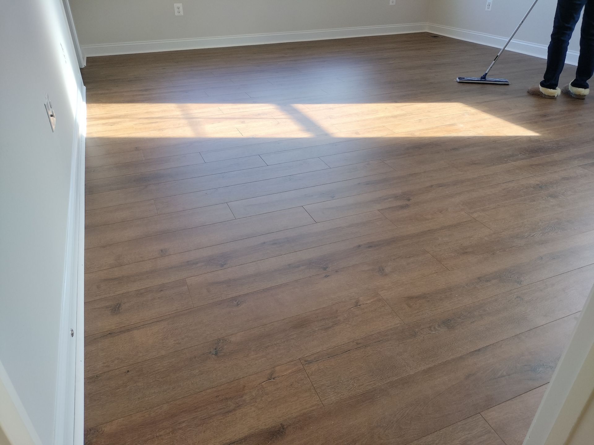 A person is cleaning a wooden floor with a mop.