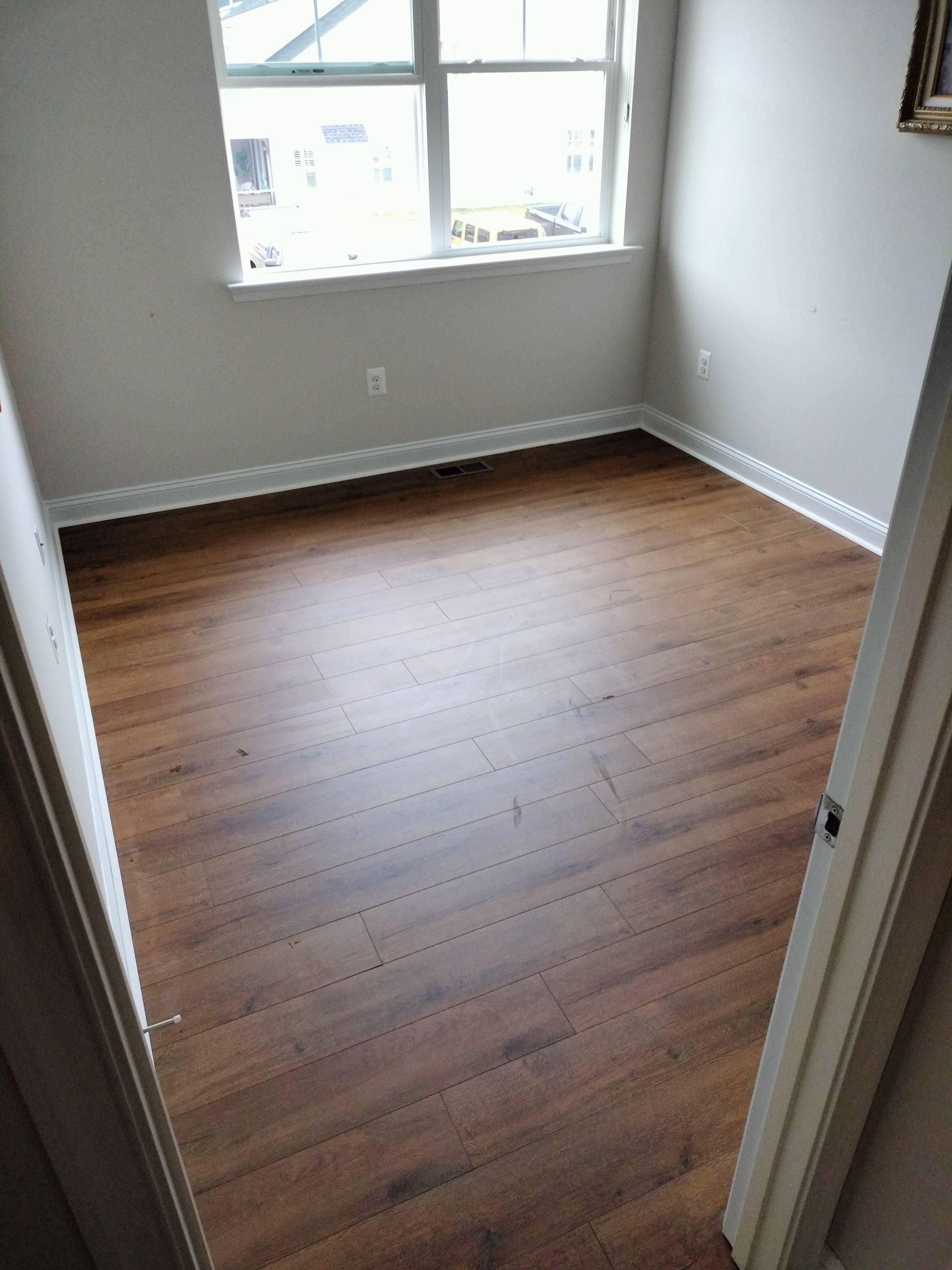 A bedroom with hardwood floors and a window.