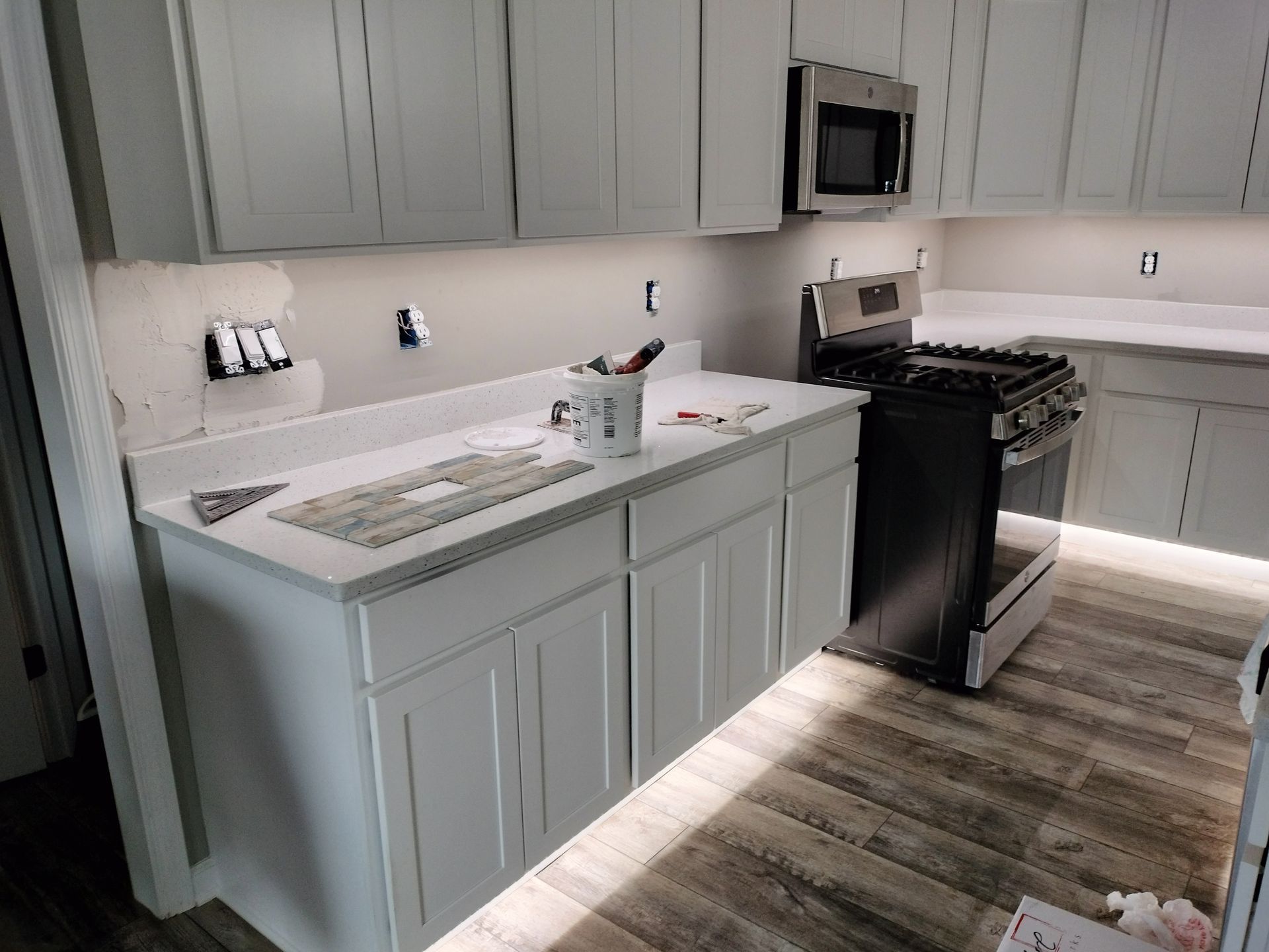 A kitchen with white cabinets , a stove , and a microwave.
