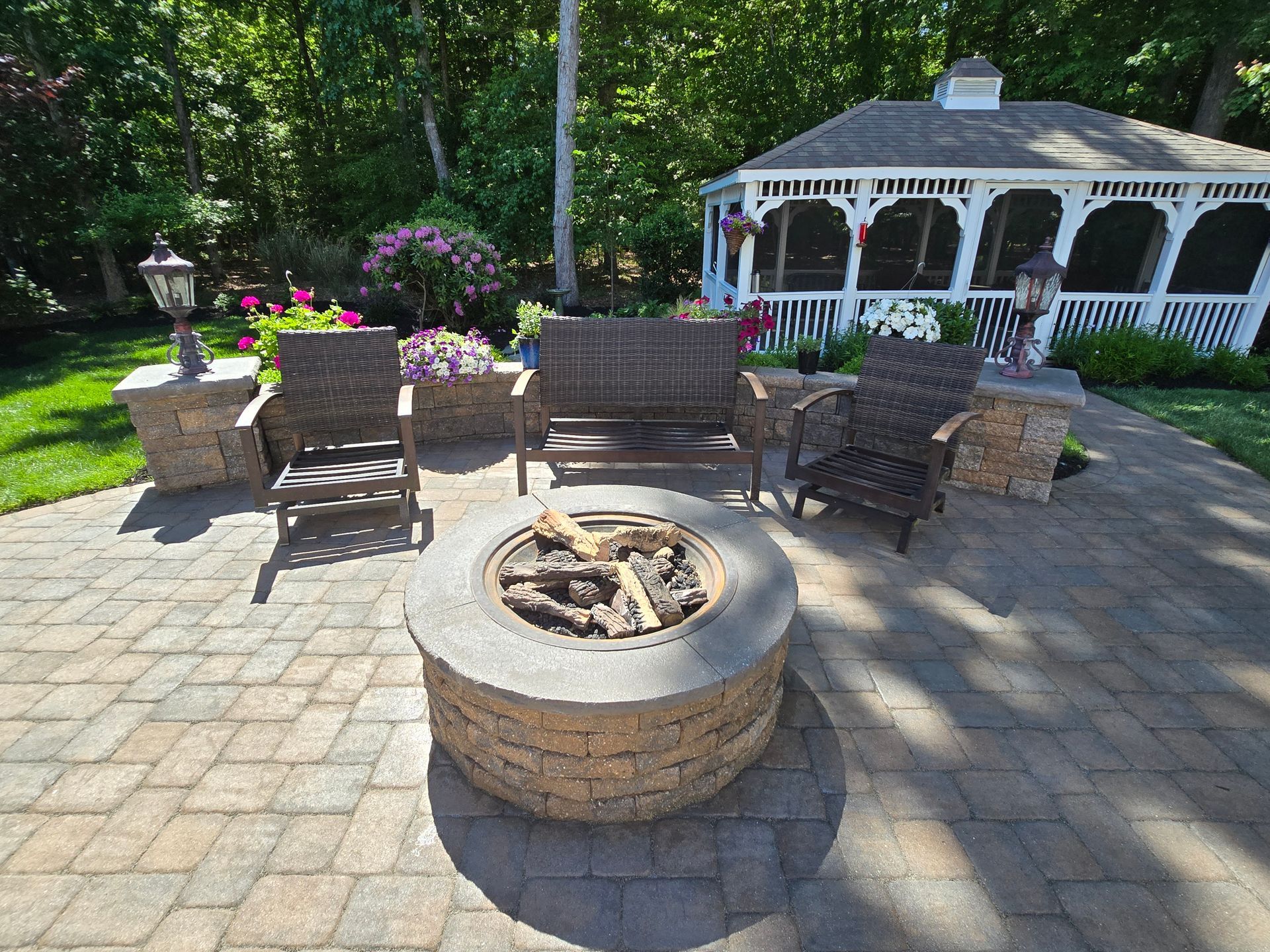 A fire pit on a patio with a gazebo in the background