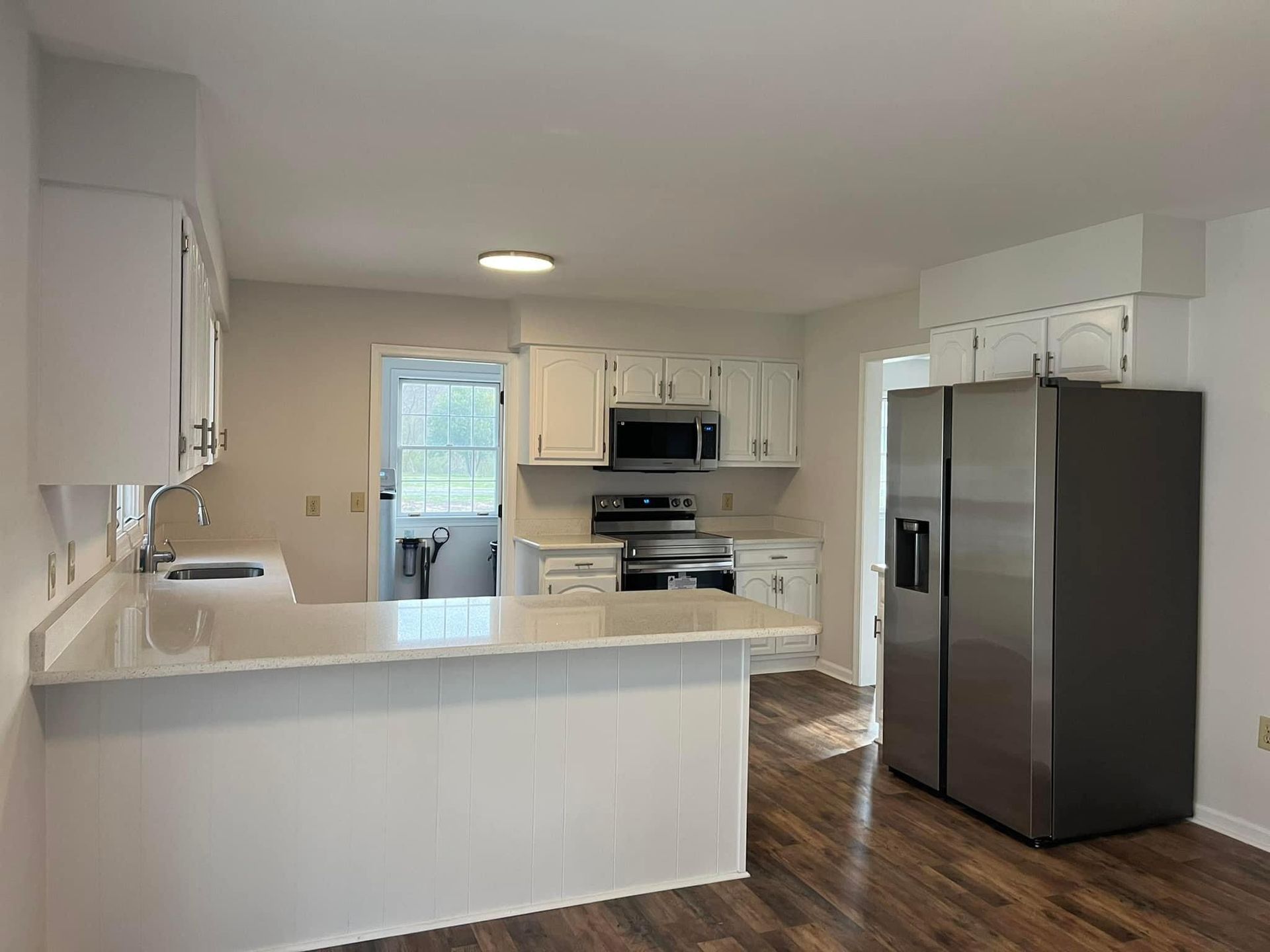 A kitchen with white cabinets , stainless steel appliances and a refrigerator.