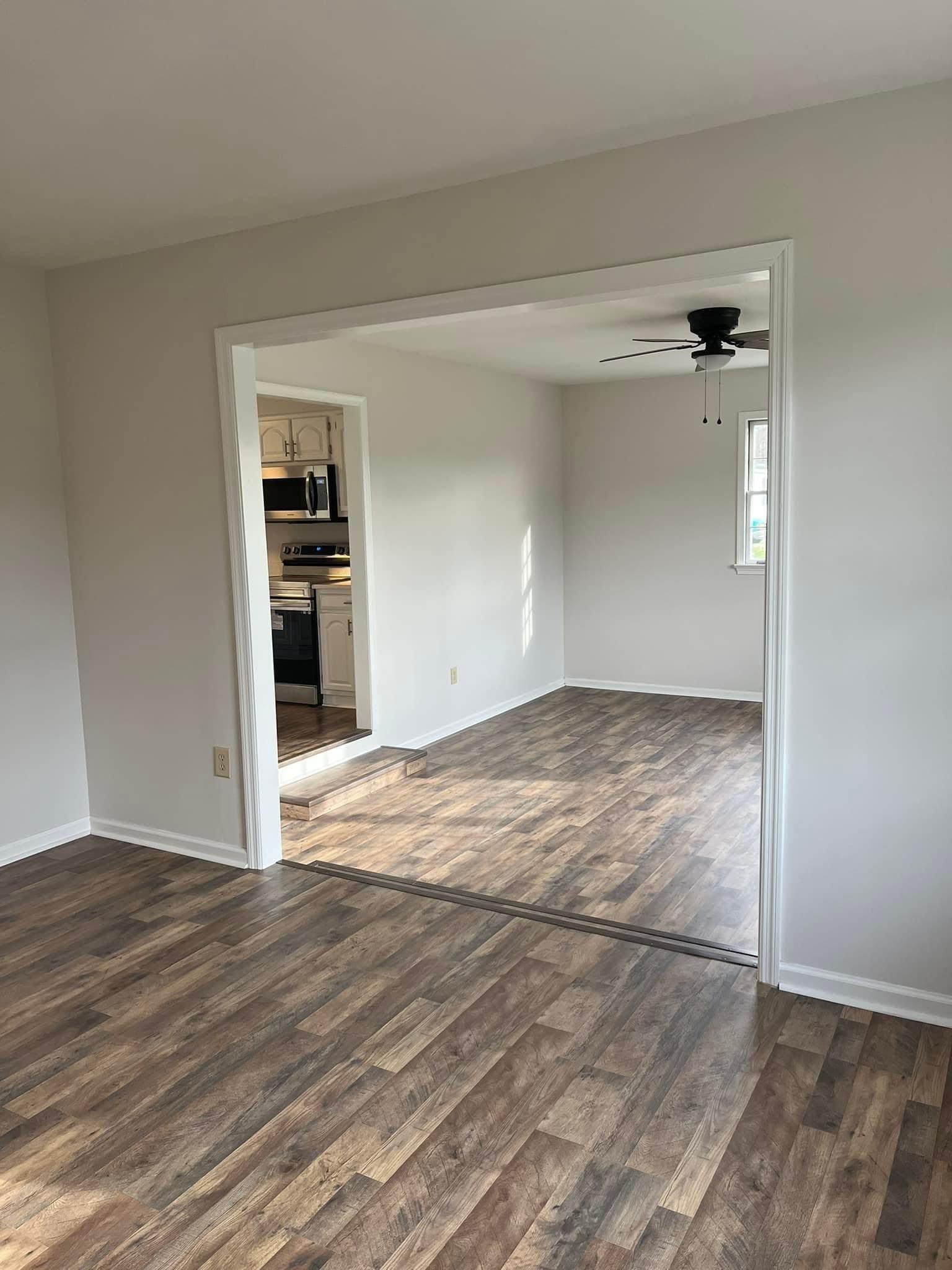 A living room with hardwood floors and a ceiling fan.