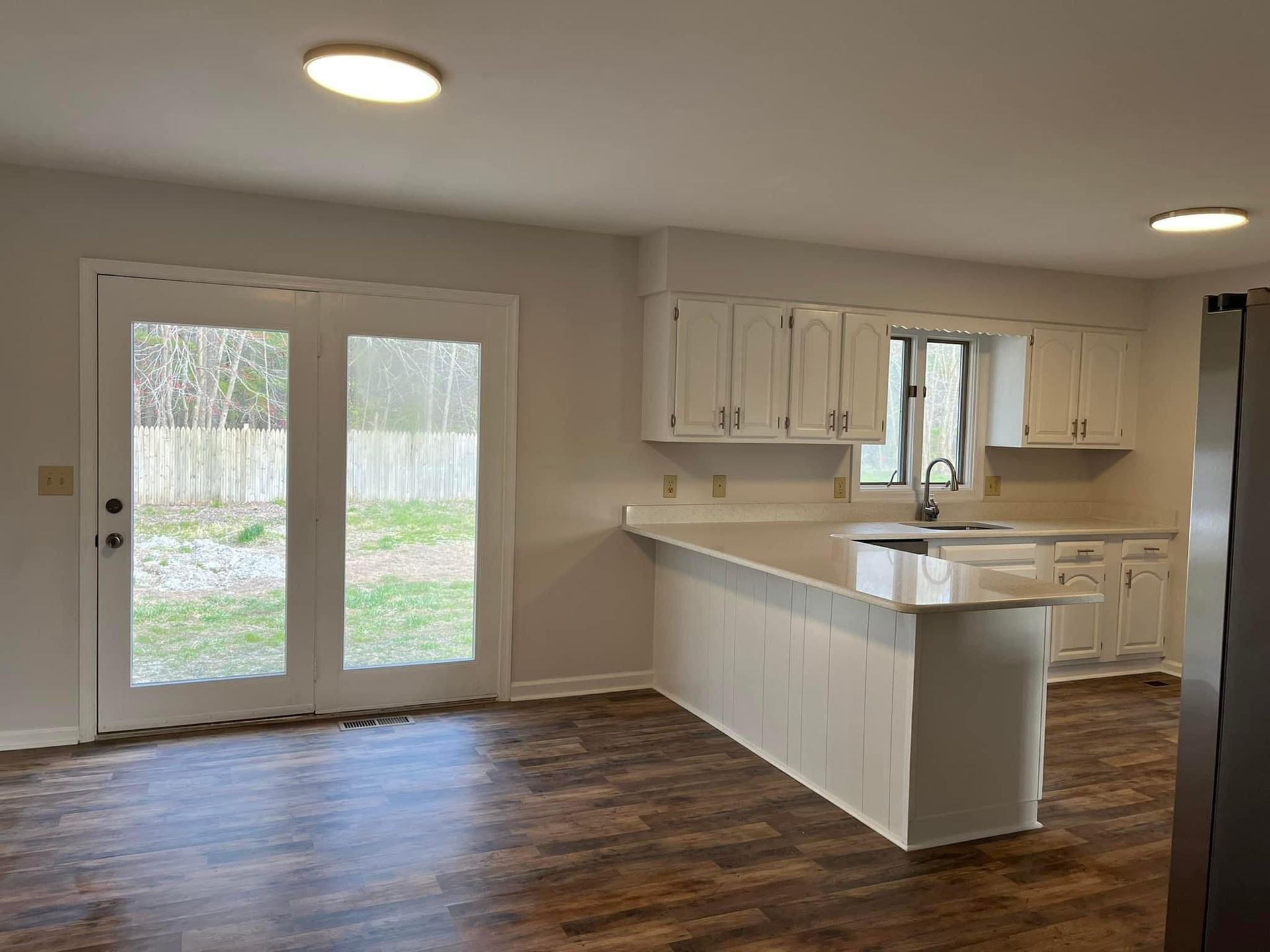 A kitchen with white cabinets , granite counter tops , and hardwood floors.