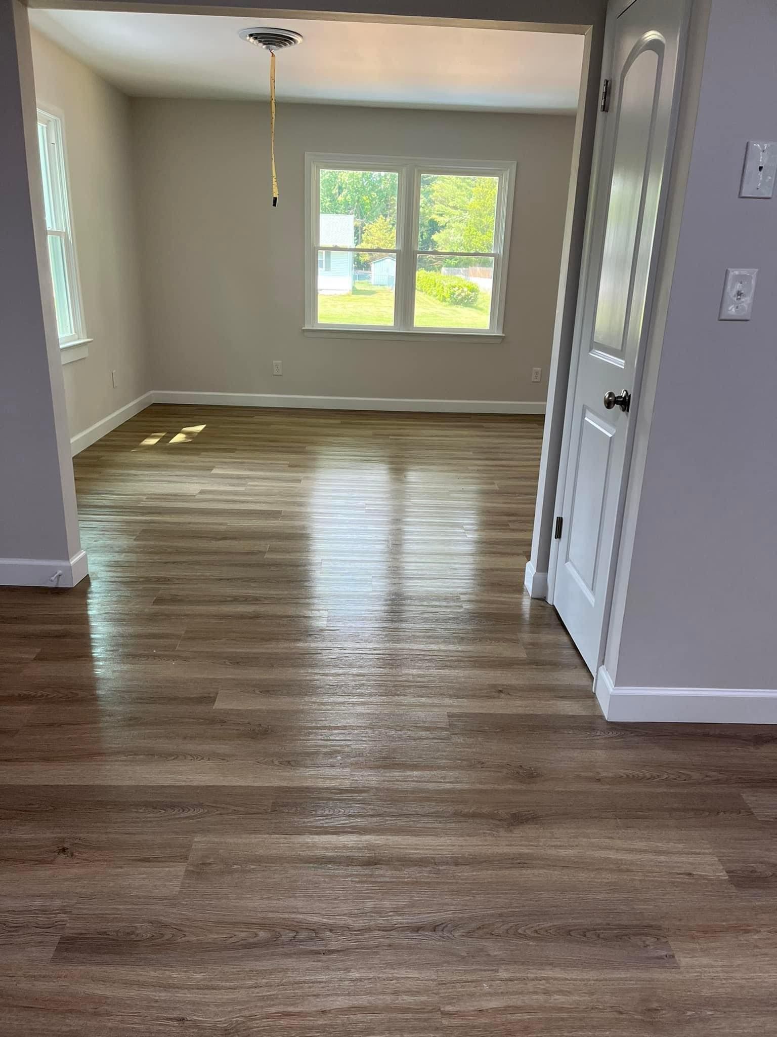 A living room with hardwood floors and two windows.