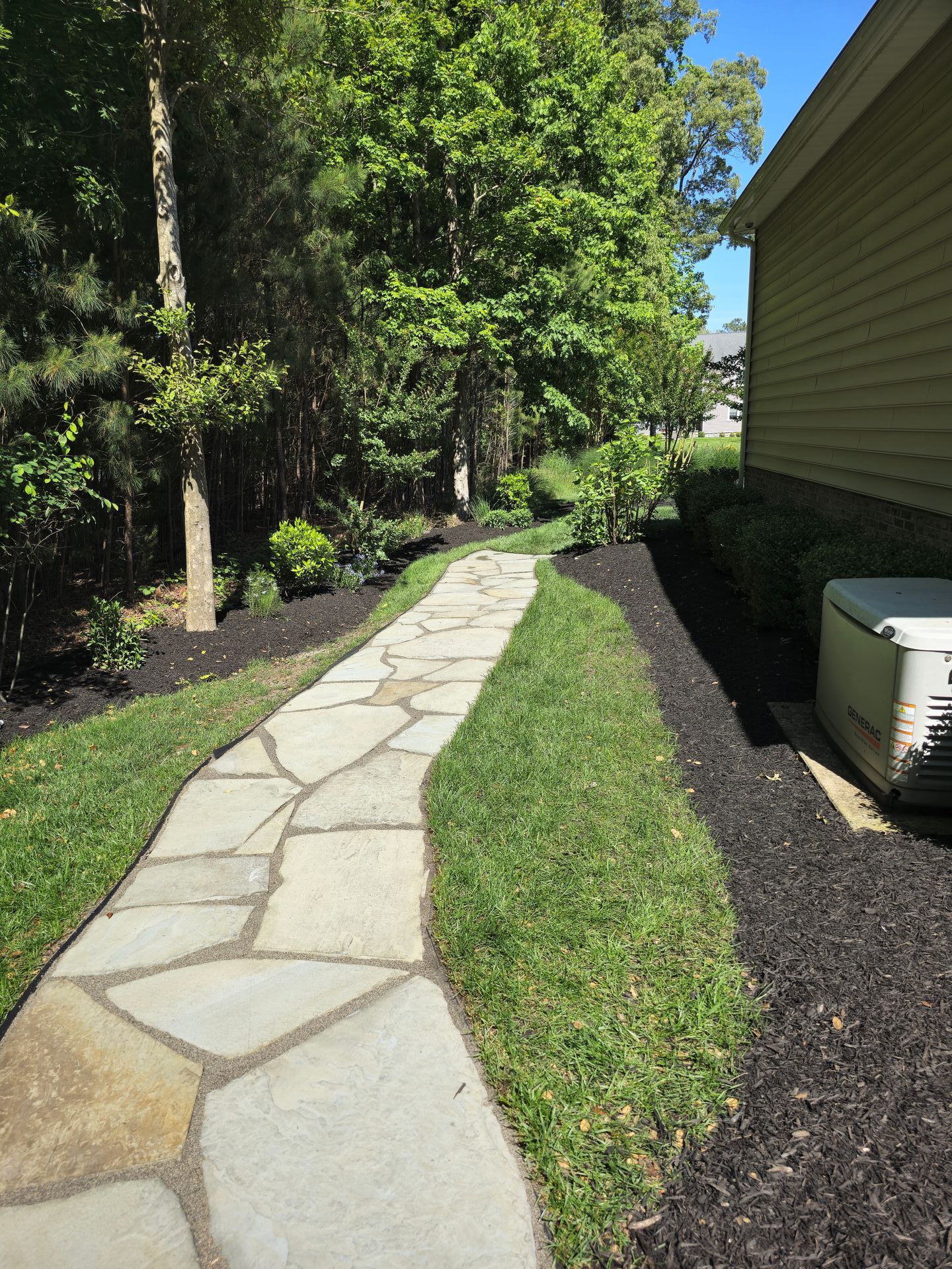 A stone walkway leading to a house in the woods.