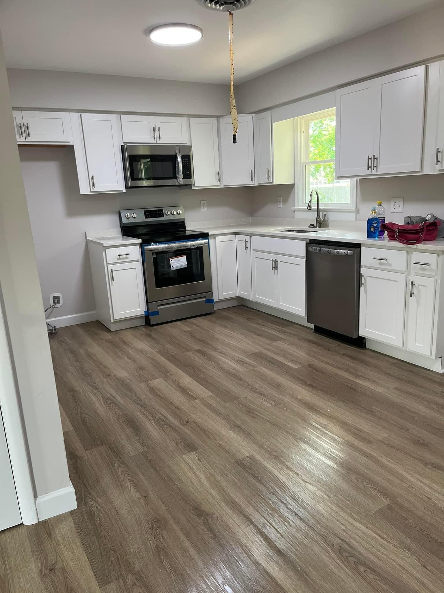 A kitchen with white cabinets , stainless steel appliances , and hardwood floors.