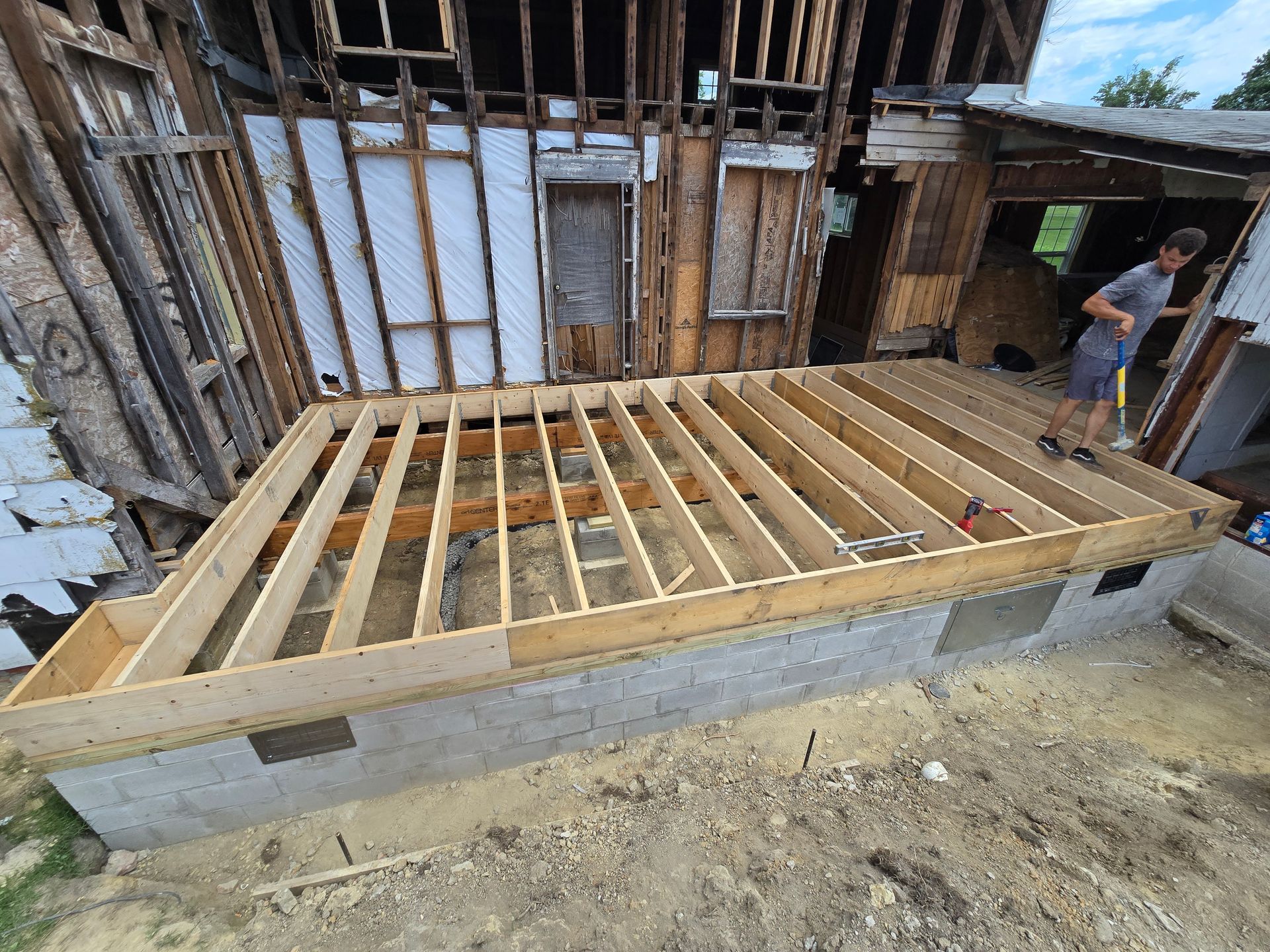 A man is standing on a wooden deck in front of a house under construction.