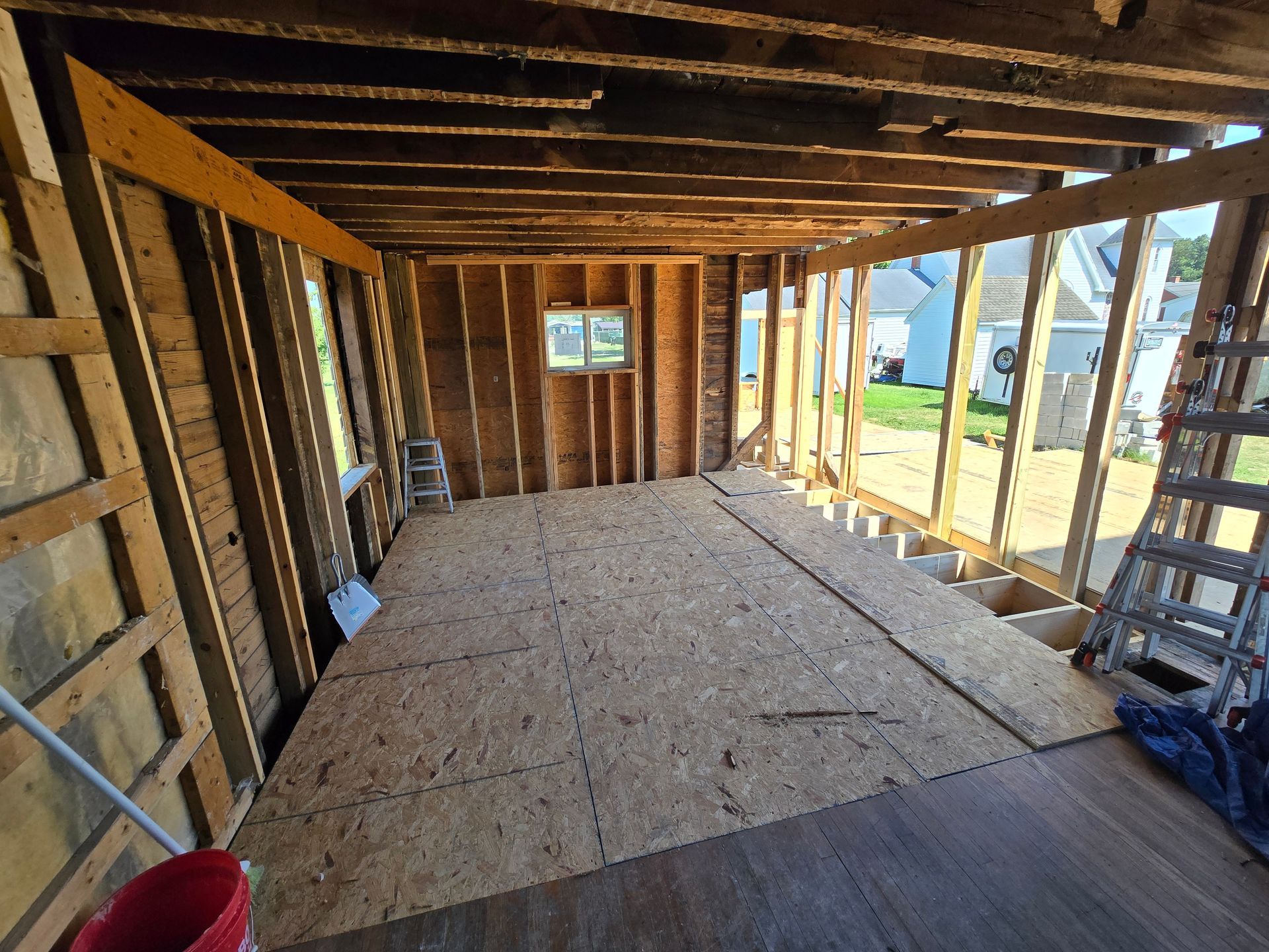A room in a house under construction with a ladder and a mop.