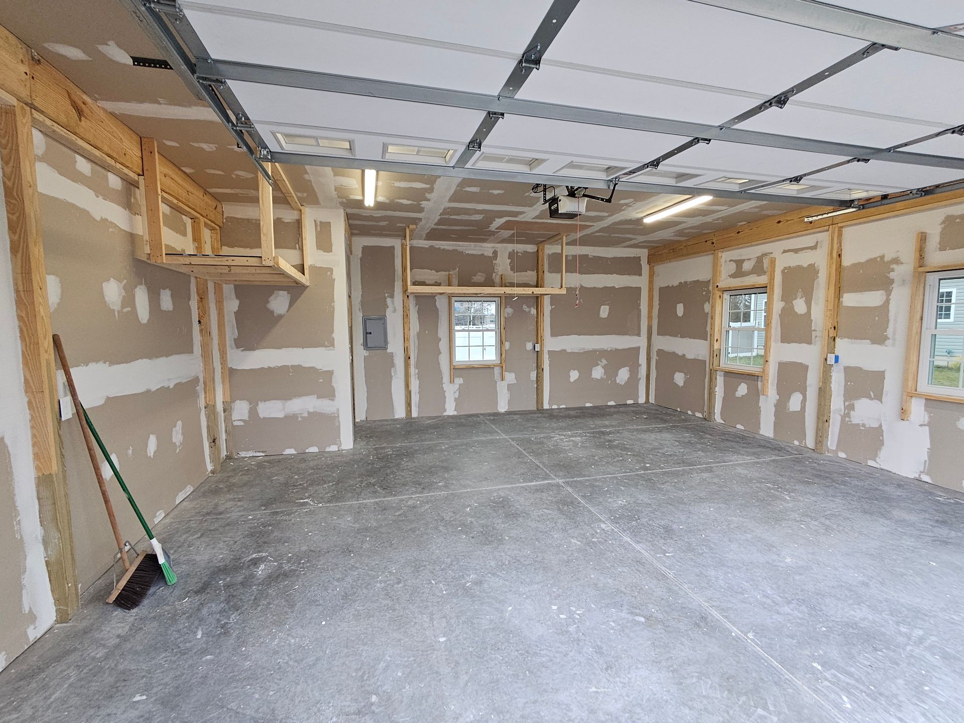 An empty garage with a broom on the floor.